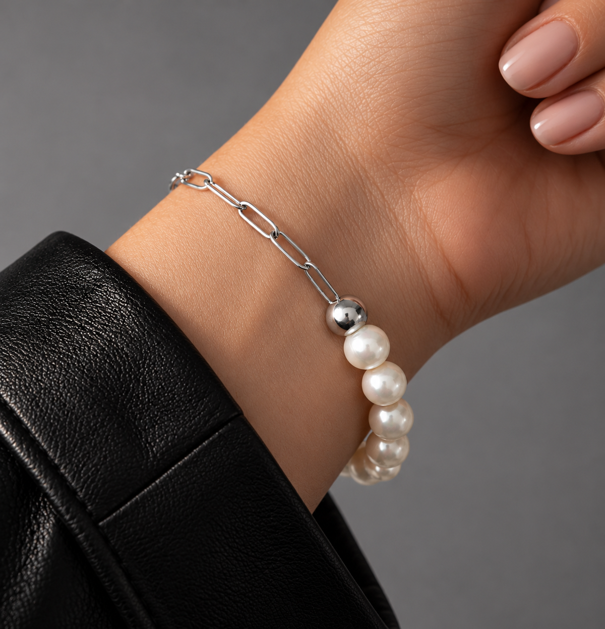 Pearl bracelet with silver chain worn on models wrist on a white background
